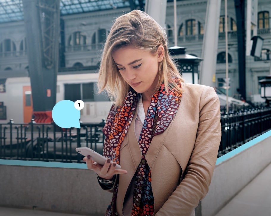 Femme avec une notification smartphone sur un quai de gare